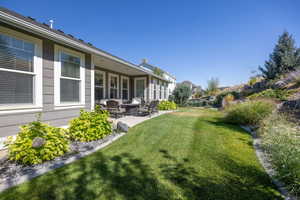 View of grassy yard featuring a patio area