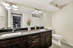 Full bath with double vanity, a chandelier, light tile patterned floors, and curtained shower