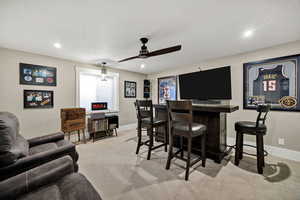 Indoor dry bar featuring light carpet, dark countertops, ceiling fan, and recessed lighting