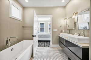 Bathroom featuring a freestanding tub, double vanity, ensuite bath, recessed lighting, and light tile patterned floors
