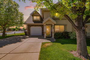 Traditional-style house featuring driveway, a yard, stone siding, and a shingled roof