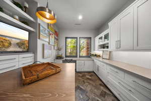 Kitchen featuring stone finish floors, open shelves, white cabinets, backsplash, and light countertops