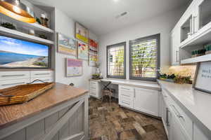 Office with built in desk and stone finish floors