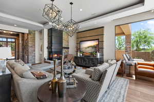 Living room featuring wood finished floors, a large fireplace, recessed lighting, and a raised ceiling