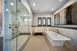 Bathroom with wainscoting, a freestanding bath, a stall shower, tile walls, and recessed lighting