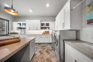 Washroom featuring separate washer and dryer, cabinet space, recessed lighting, and stone finish floors