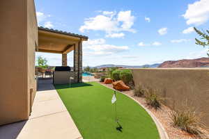 View of yard featuring a putting area, a mountain view, and a patio