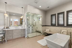 Full bathroom with wainscoting, a shower stall, a freestanding tub, and vanity