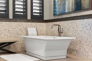 Full bath featuring a freestanding bath, a wainscoted wall, and tile walls