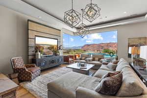 Living room featuring wood finished floors, a tray ceiling, recessed lighting, a mountain view, and a chandelier