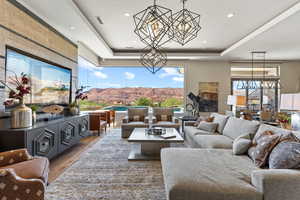 Living area with a chandelier, a raised ceiling, plenty of natural light, and recessed lighting