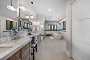 Full bathroom featuring double vanity, a soaking tub, a stall shower, and recessed lighting