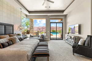 Living area with carpet, a raised ceiling, and a ceiling fan
