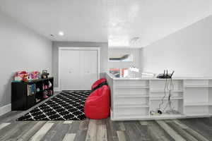Loft with wood finished floors, a textured ceiling, and a closet