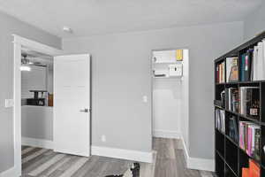 Unfurnished office with a textured ceiling, wood finished floors, and ceiling fan