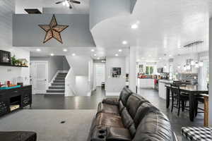 Living room with a textured ceiling, a ceiling fan, stairs, recessed lighting, and a chandelier