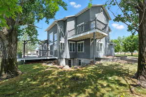 View of side of home with a balcony, a yard, a wooden deck, and stucco siding