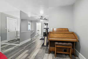 Loft featuring wood finished floors, a textured ceiling, and ceiling fan