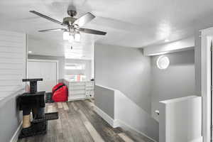 Hall with an upstairs landing, a textured ceiling, wood finished floors, and recessed lighting