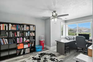 Office area featuring wood finished floors, a textured ceiling, and ceiling fan