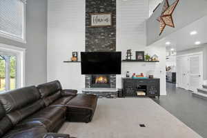 Living room featuring a towering ceiling, a tile fireplace, recessed lighting, and wood finished floors