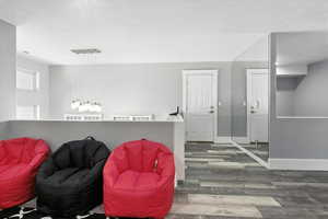 Loft featuring a textured ceiling and wood finished floors