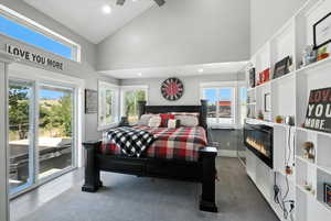 Bedroom with access to outside, recessed lighting, a glass covered fireplace, high vaulted ceiling, and tile patterned floors