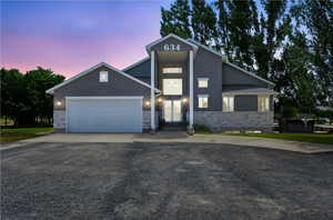 View of front of home with stone siding, stucco siding, driveway, and an attached garage