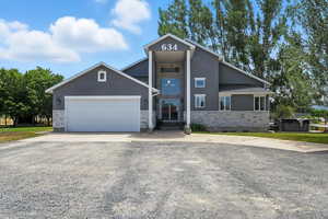View of front of property with stone siding, stucco siding, concrete driveway, and a garage