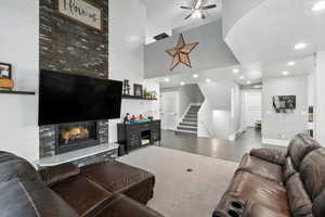 Living room with stairs, a tiled fireplace, a towering ceiling, recessed lighting, and ceiling fan