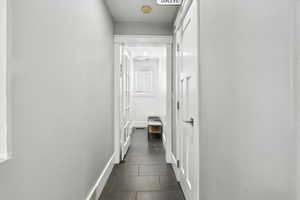 Hallway with dark tile patterned floors and baseboards