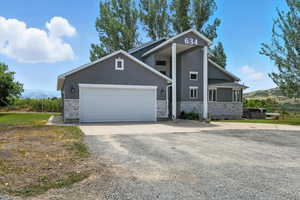 View of front of home featuring stone siding, driveway, stucco siding, a garage, and a mountain view
