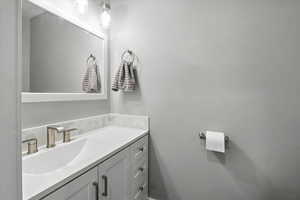 Half bathroom featuring vanity and tasteful backsplash