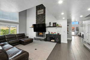 Living room with a textured ceiling, a high ceiling, a fireplace, and tile patterned flooring
