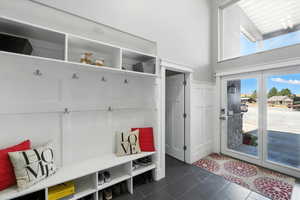 Mudroom featuring dark tile patterned flooring and a towering ceiling