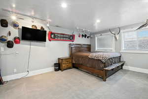 Bedroom with carpet floors, a textured ceiling, and track lighting