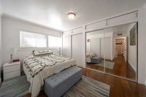 Bedroom with crown molding, wood finished floors, and multiple closets