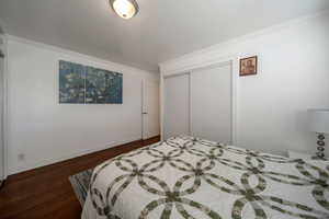 Bedroom featuring crown molding, wood finished floors, and a closet