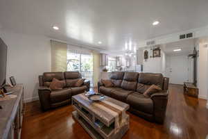 Living room featuring crown molding, dark wood-type flooring, and recessed lighting