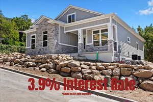 View of front of house featuring board and batten siding, stone siding, and covered porch