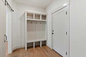 Mudroom with light wood finished floors and a barn door