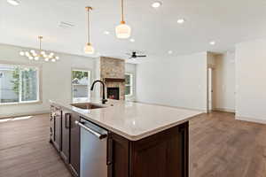 Kitchen with dishwasher, open floor plan, a stone fireplace, light wood-style flooring