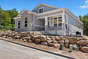 View of front of property featuring board and batten siding, stone siding, and covered porch
