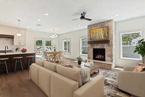 Living room featuring wood finished floors, a fireplace, a ceiling fan, recessed lighting, and a chandelier