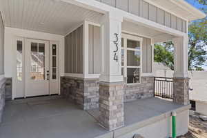 Property entrance with covered porch, board and batten siding, and stone siding