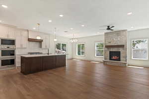 Kitchen with stainless steel appliances, dark wood-style flooring, open floor plan, light countertops, and recessed lighting