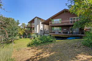 Back of property with a balcony and a lawn