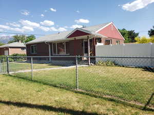 View of front facade with brick siding, a fenced backyard, and a shingled roof