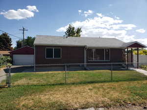 View of front of home featuring brick siding, roof with shingles, a fenced backyard, and a garage