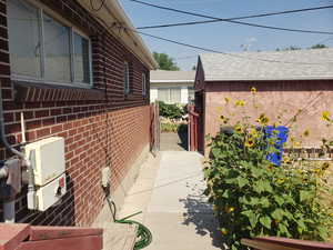 View of side of property with a shingled roof and brick siding